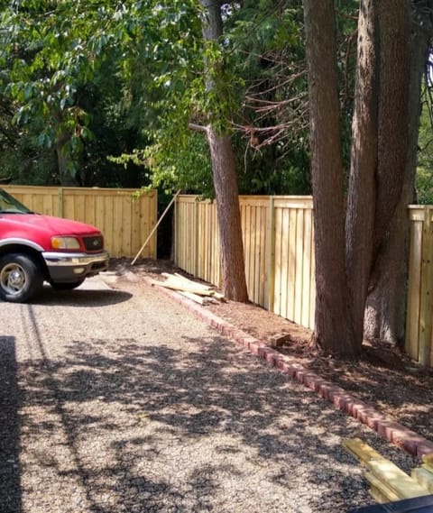 wood privacy fence around trees gravel driveway